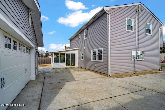 back of property with a patio, a garage, and a sunroom