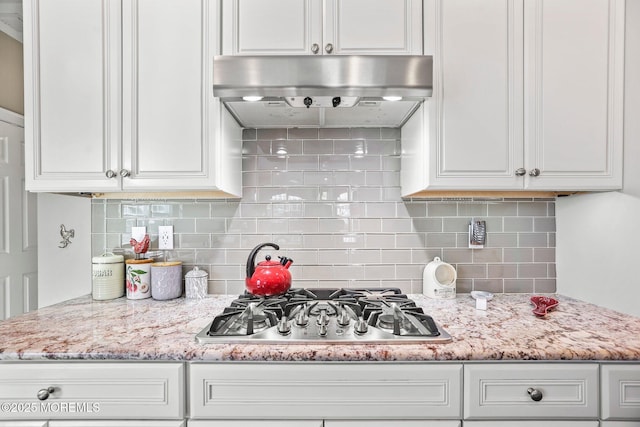 kitchen featuring white cabinetry, stainless steel gas stovetop, ventilation hood, and light stone countertops