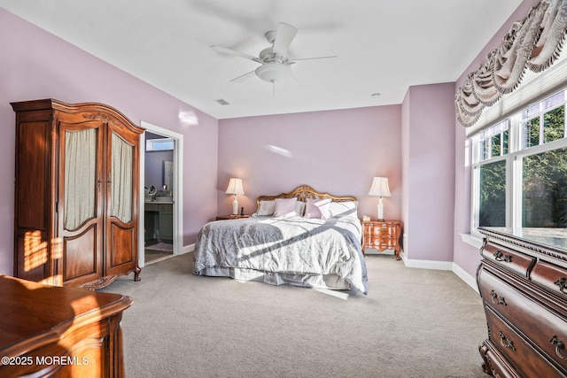 bedroom with ceiling fan, ensuite bathroom, and light carpet