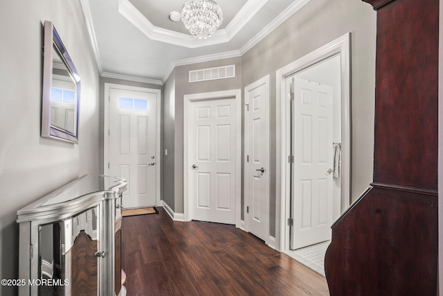 corridor with ornamental molding, dark hardwood / wood-style floors, a tray ceiling, and a notable chandelier