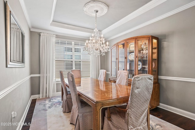 dining room featuring crown molding, dark hardwood / wood-style floors, a chandelier, and a tray ceiling