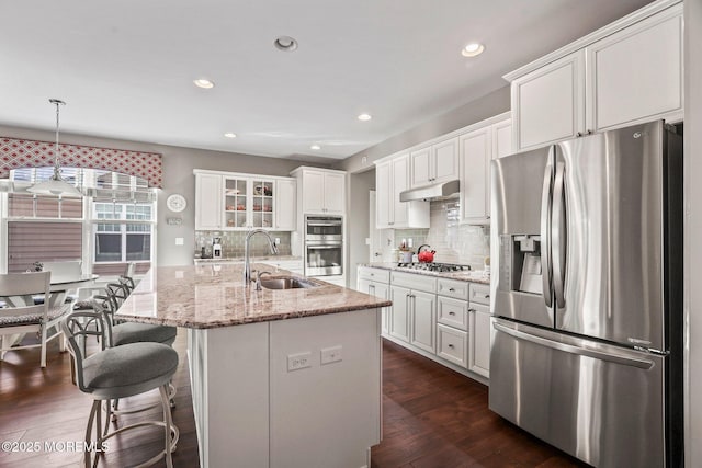 kitchen featuring sink, white cabinetry, hanging light fixtures, appliances with stainless steel finishes, and a kitchen island with sink