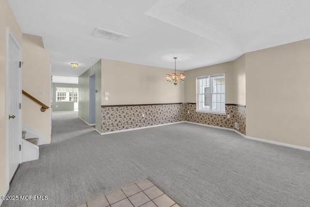 spare room with an inviting chandelier, plenty of natural light, and light colored carpet