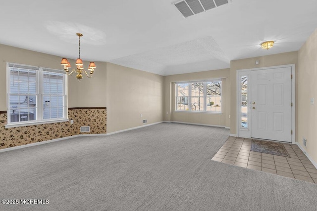 carpeted foyer entrance with an inviting chandelier