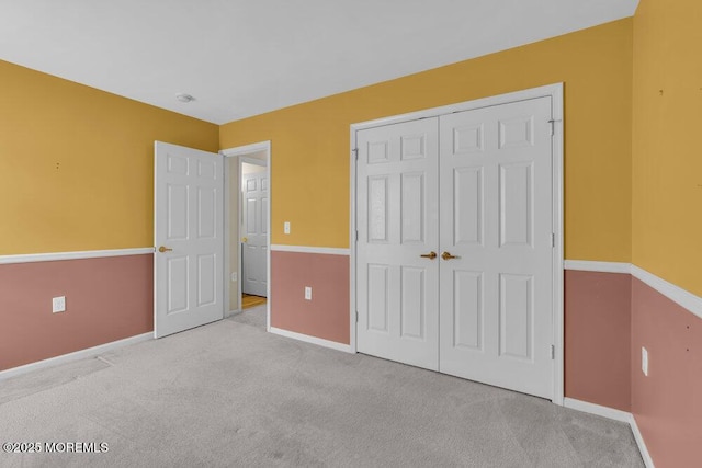 unfurnished bedroom with light colored carpet and a closet