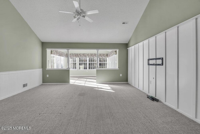 carpeted spare room featuring ceiling fan, lofted ceiling, a textured ceiling, and a wealth of natural light