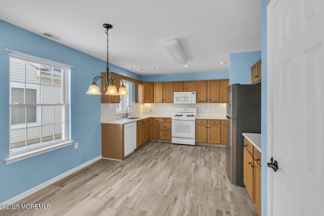 kitchen with sink, decorative light fixtures, white appliances, light hardwood / wood-style floors, and decorative backsplash