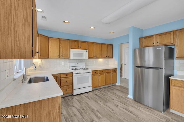 kitchen featuring sink, white appliances, light hardwood / wood-style flooring, and decorative backsplash