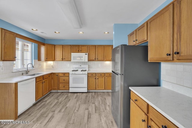 kitchen featuring tasteful backsplash, sink, white appliances, and light hardwood / wood-style flooring