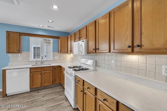 kitchen featuring backsplash, white appliances, sink, and light wood-type flooring