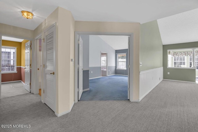 hallway featuring light colored carpet and lofted ceiling