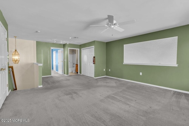 carpeted empty room featuring track lighting and ceiling fan with notable chandelier