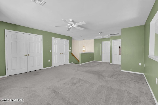 unfurnished living room with ceiling fan, rail lighting, and light carpet