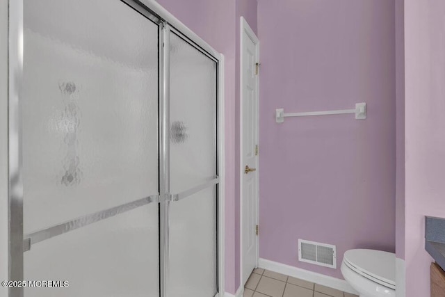 bathroom featuring tile patterned flooring, a shower with shower door, and toilet