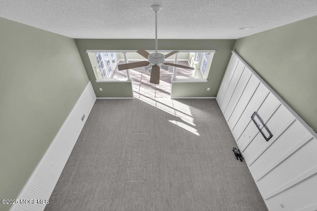 unfurnished dining area featuring ceiling fan, light carpet, a wealth of natural light, and a textured ceiling