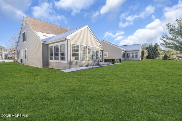 rear view of property featuring a lawn and a sunroom