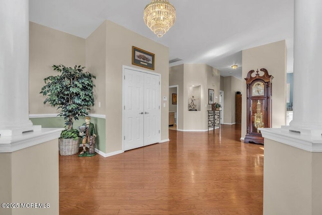 foyer entrance with ornate columns, hardwood / wood-style floors, and a chandelier