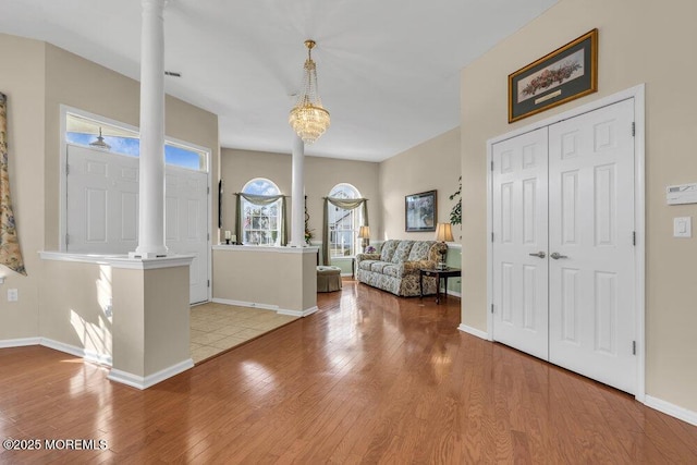 foyer entrance with ornate columns, a chandelier, and light hardwood / wood-style floors