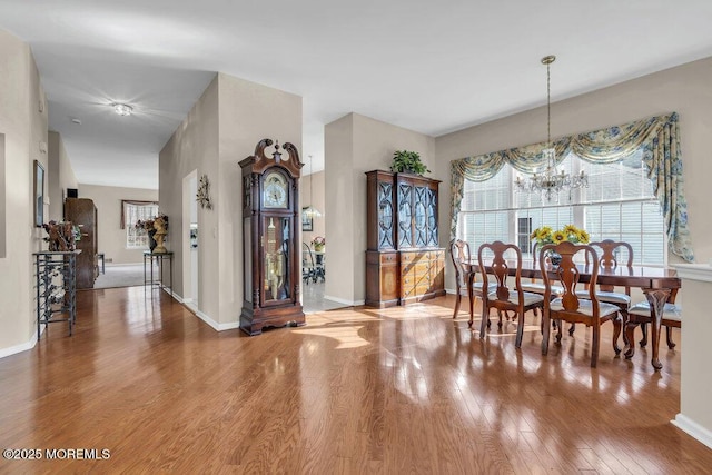 dining room featuring wood-type flooring, a healthy amount of sunlight, and an inviting chandelier