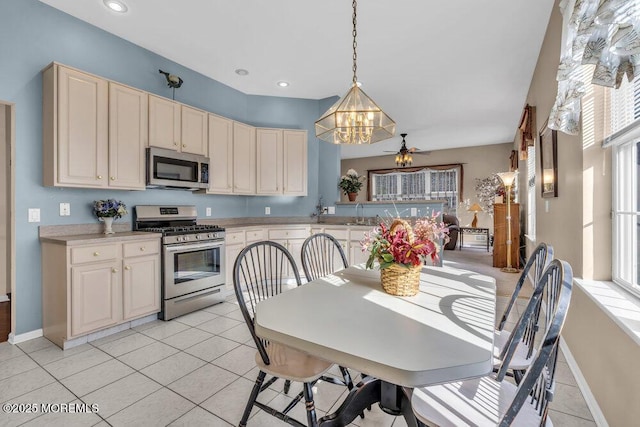 kitchen with pendant lighting, light tile patterned floors, cream cabinets, and appliances with stainless steel finishes