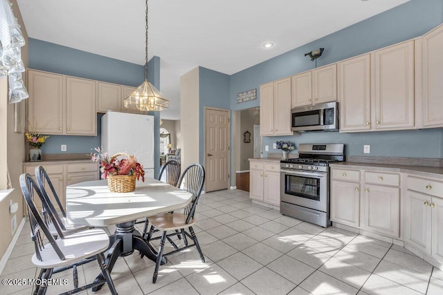 kitchen with stainless steel appliances, cream cabinets, light tile patterned floors, and decorative light fixtures