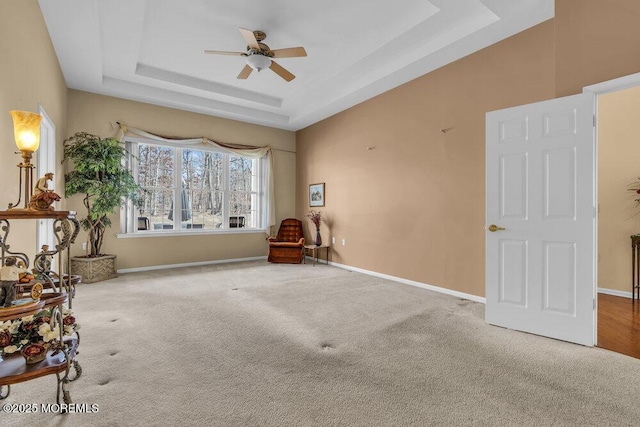 interior space with ceiling fan, a raised ceiling, and carpet floors