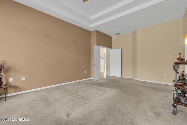 carpeted spare room featuring a raised ceiling and ceiling fan