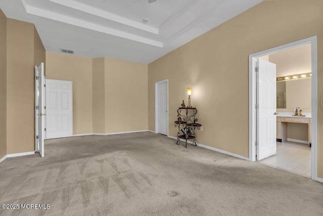 carpeted spare room featuring a high ceiling and a tray ceiling