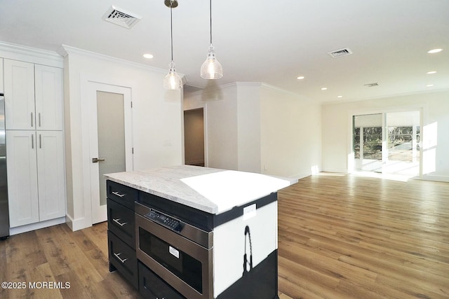 kitchen with a center island, white cabinets, crown molding, hanging light fixtures, and light hardwood / wood-style floors