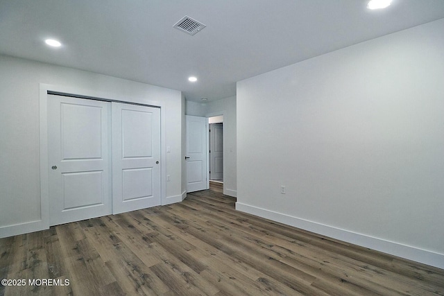 unfurnished bedroom featuring a closet and dark wood-type flooring