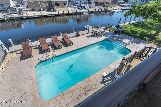 view of swimming pool with a patio area and a water view