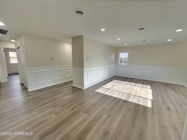 spare room with a baseboard heating unit and light hardwood / wood-style flooring