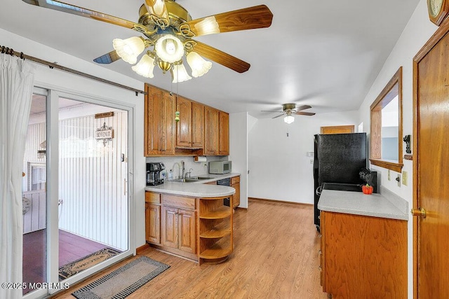 kitchen featuring ceiling fan, sink, black appliances, and light wood-type flooring