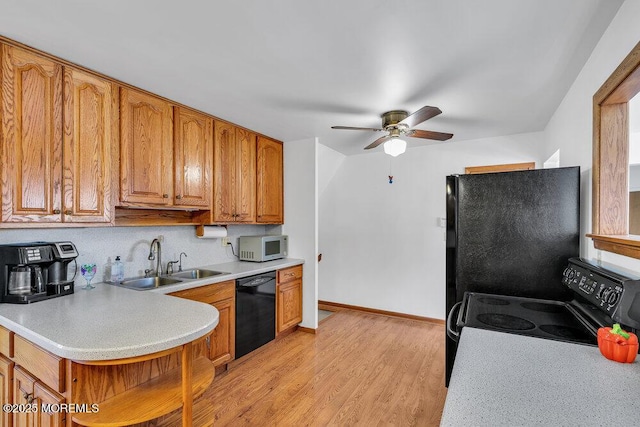 kitchen featuring light wood-type flooring, sink, ceiling fan, and black appliances