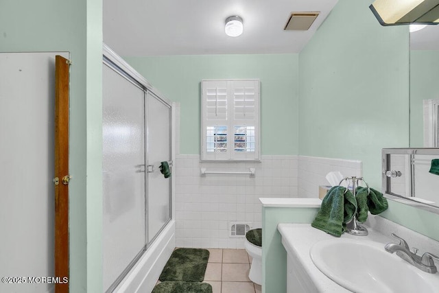 full bathroom featuring bath / shower combo with glass door, vanity, tile walls, tile patterned flooring, and toilet