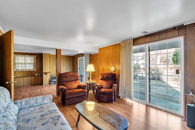 living room featuring wooden walls and light hardwood / wood-style flooring