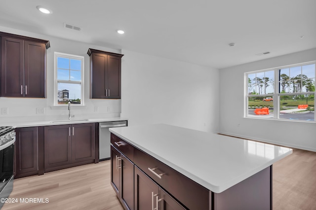 kitchen featuring dark brown cabinetry, sink, light hardwood / wood-style floors, a kitchen island, and appliances with stainless steel finishes