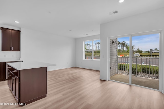 interior space with dark brown cabinetry, a center island, and light wood-type flooring