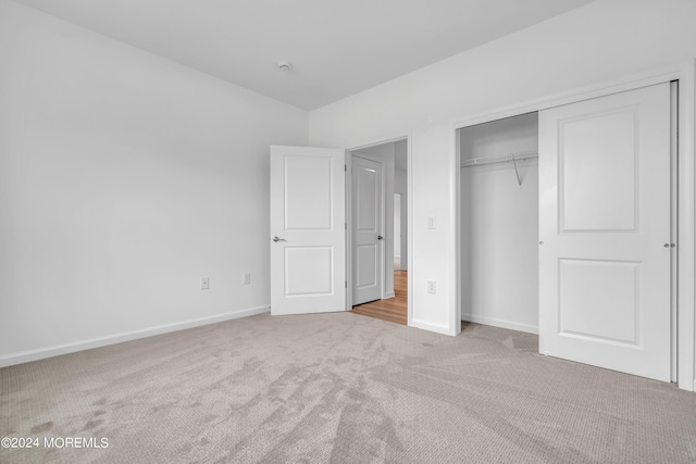 unfurnished bedroom featuring light carpet and a closet