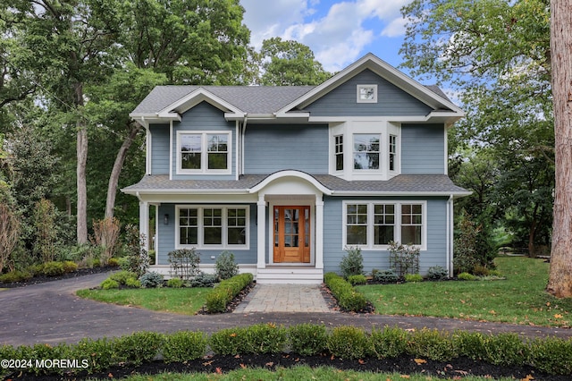 view of front of property with a shingled roof and a front yard