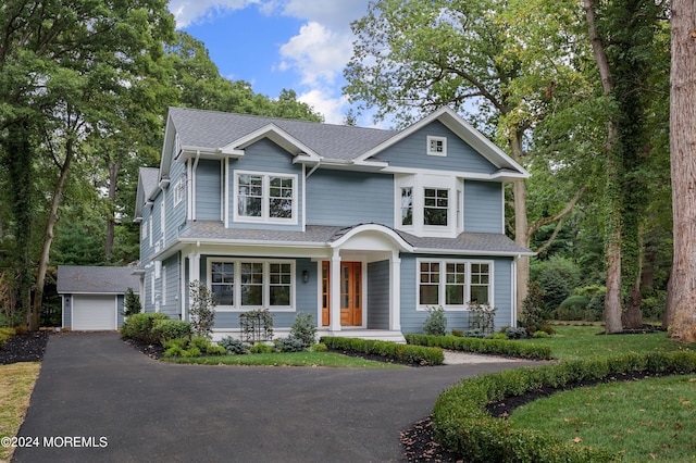 view of front of house featuring a porch, a garage, a shingled roof, an outdoor structure, and a front lawn