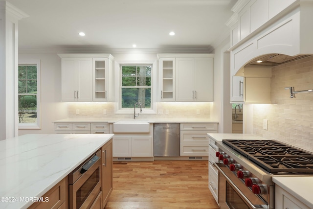 kitchen featuring appliances with stainless steel finishes, light stone counters, crown molding, sink, and white cabinetry