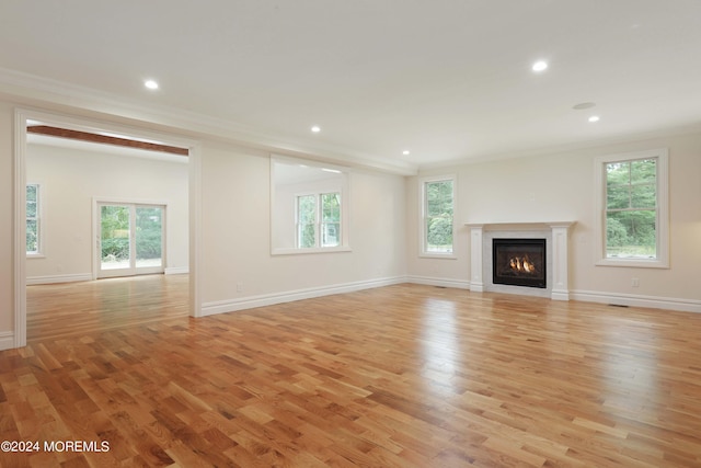 unfurnished living room with light hardwood / wood-style flooring and crown molding