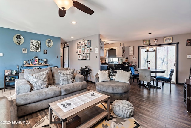 living room featuring ceiling fan with notable chandelier and hardwood / wood-style flooring