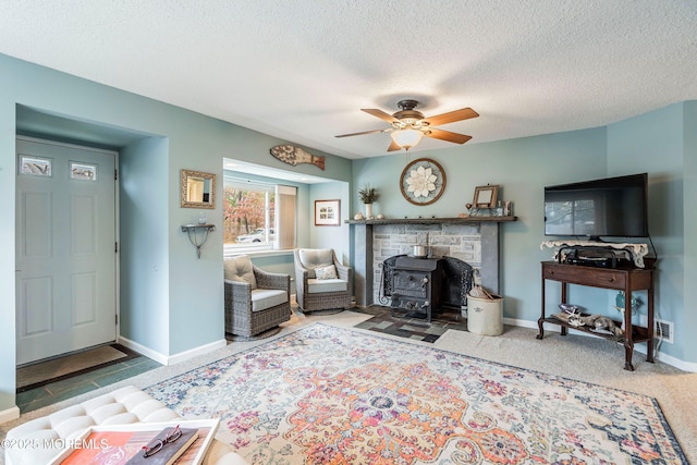 living room with a textured ceiling, a wood stove, and ceiling fan