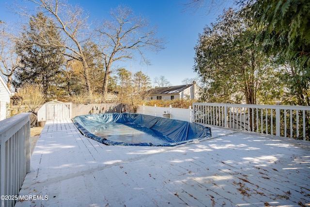 wooden deck featuring a shed and a covered pool