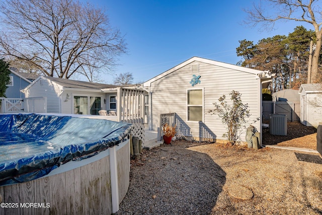 rear view of property featuring central AC and a covered pool