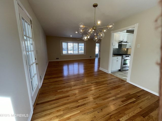 unfurnished dining area featuring light wood-type flooring and an inviting chandelier