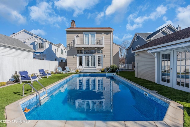 back of house with a balcony, french doors, a lawn, and a fenced in pool