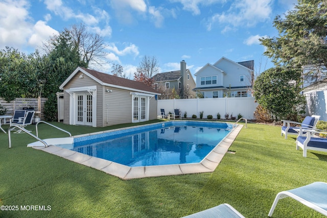 view of swimming pool with a lawn, french doors, and an outbuilding